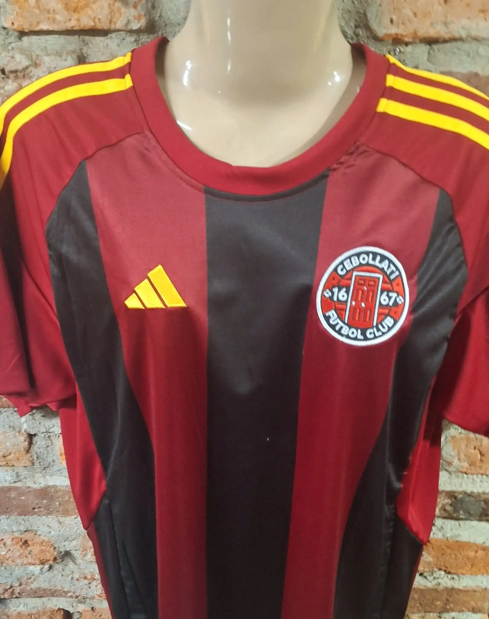 Camiseta de Cebollati Fútbol Club a rayas rojas y negras con el escudo del club bordado en el pecho