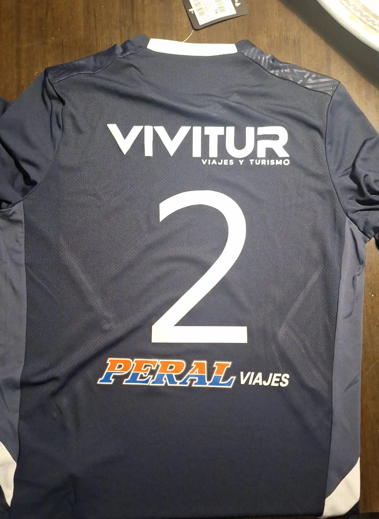 Espalda de camiseta azul marino con el sponsor Vivitur, el número 2 y el logo de Peral Viajes