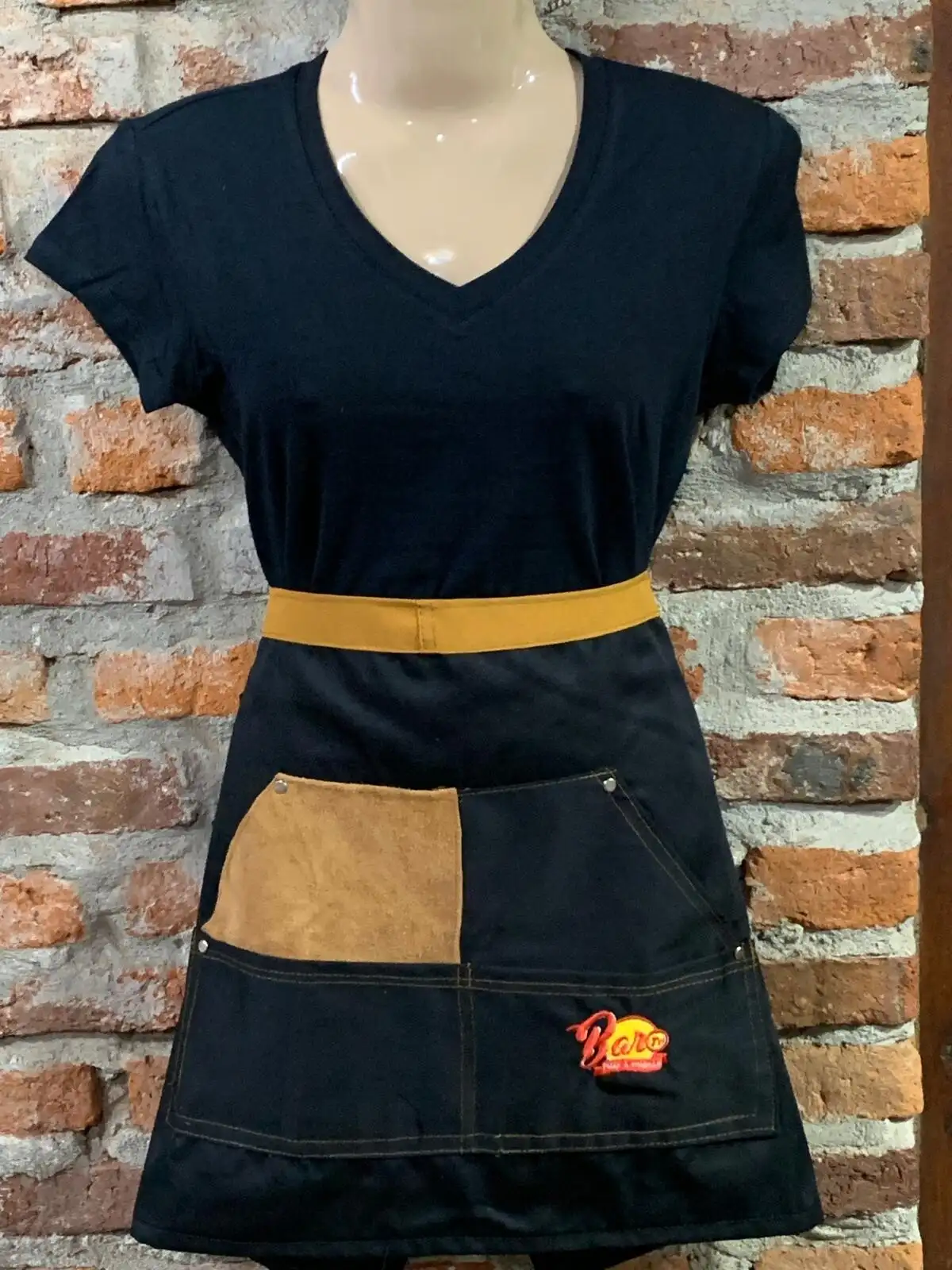 Delantal negro con cintura mostaza y bolsillo de cuero, con el logo de Bar 71 bordado a color