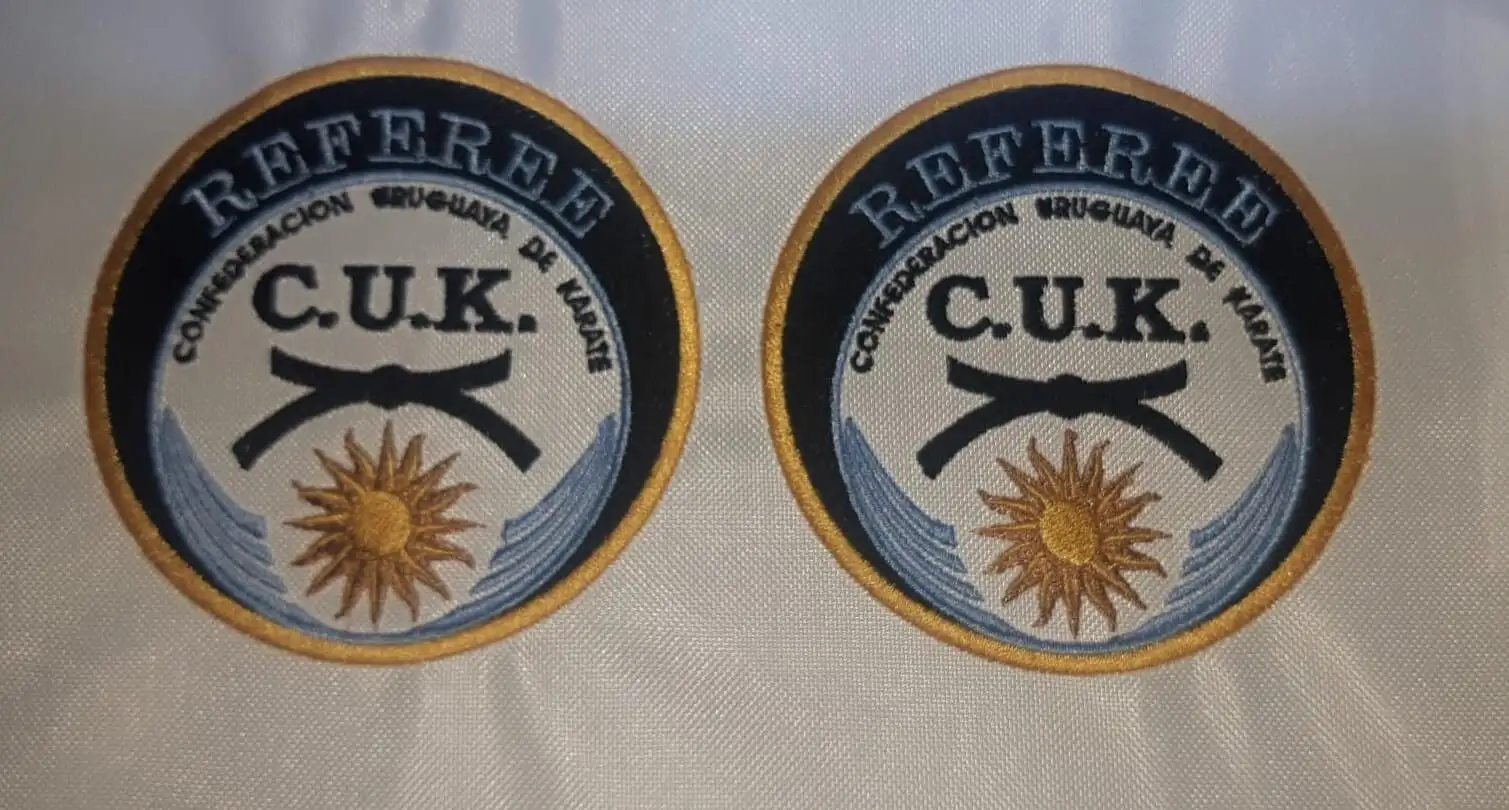 Dos parches bordados de referee de la Confederación Uruguaya de Karate, con cinturón negro y sol de mayo