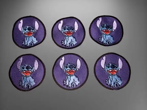 Seis parches bordados circulares violetas con un personaje azul de dibujos animados