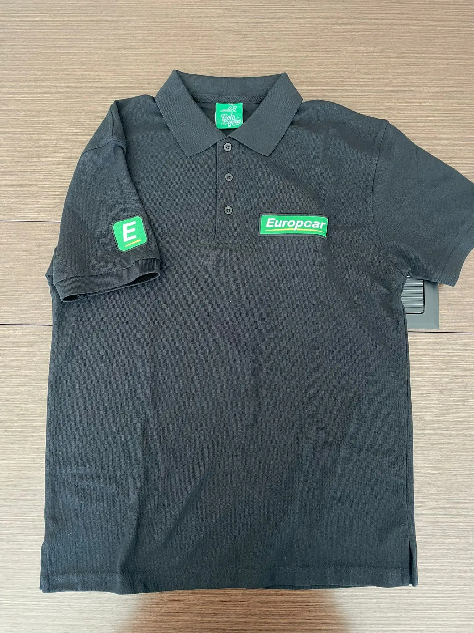 Polo negro de uniforme con el logo de Europcar bordado en el pecho y en la manga